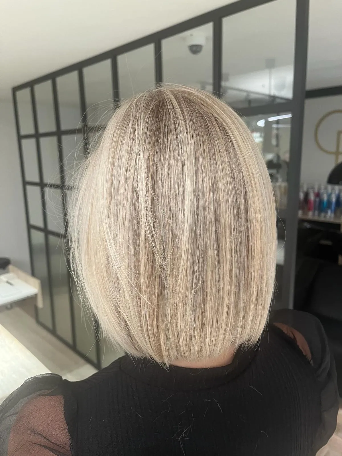 Strak geknipte blonde bob met highlights, in het salon gefotografeerd