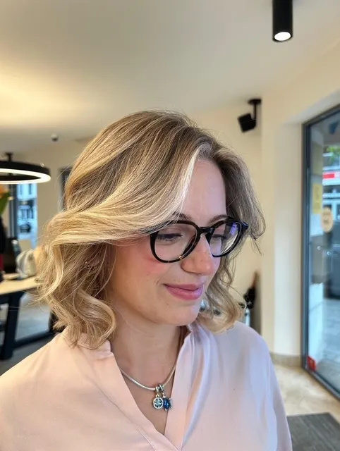 Een klant met bril en een blonde brushing met volume in het salon
